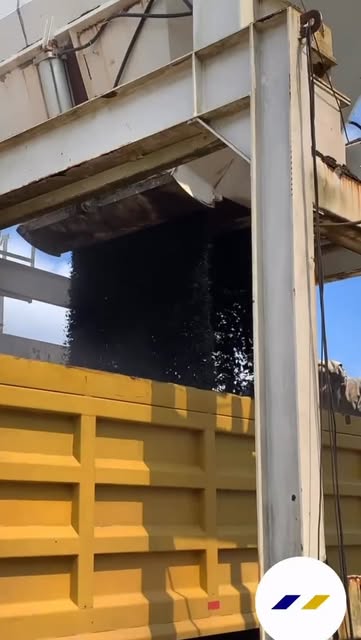Mezcla asfáltica cayendo desde la tolva de la planta a un camión amarillo