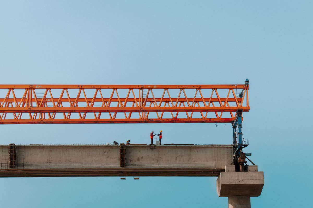 Foto de referencia: puente de concreto en construcción con una grúa lanzadora de vigas